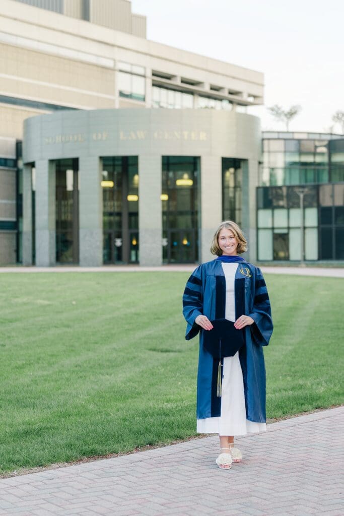 Abby holds her graduation cap and wears her gown outside of Quinnipiac Law School. 