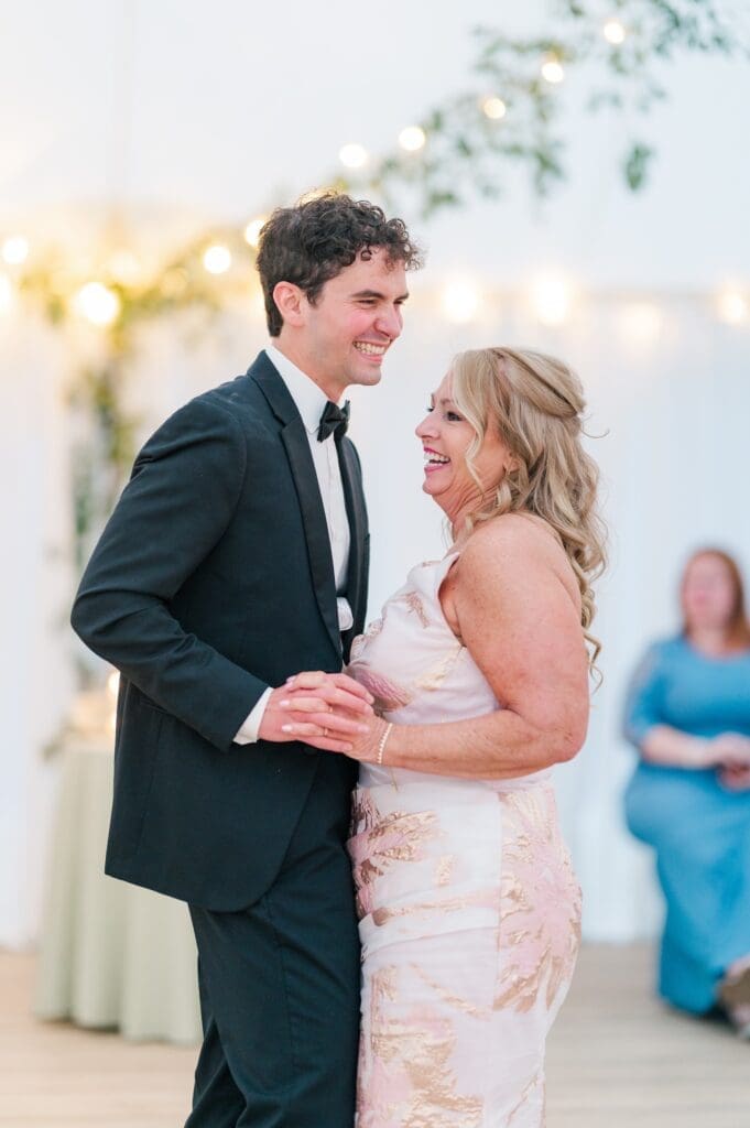 Mitch and his mom laugh as they dance together. 