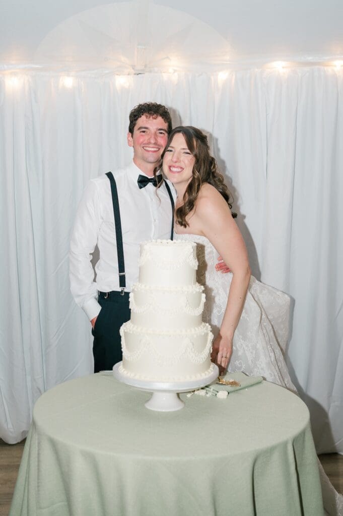 Miranda and Mitch standing behind a three tier wedding cake. 