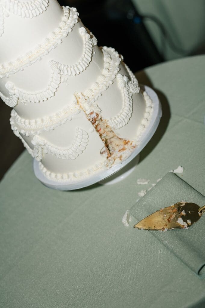 A three-tier vintage wedding cake with a piece missing. 