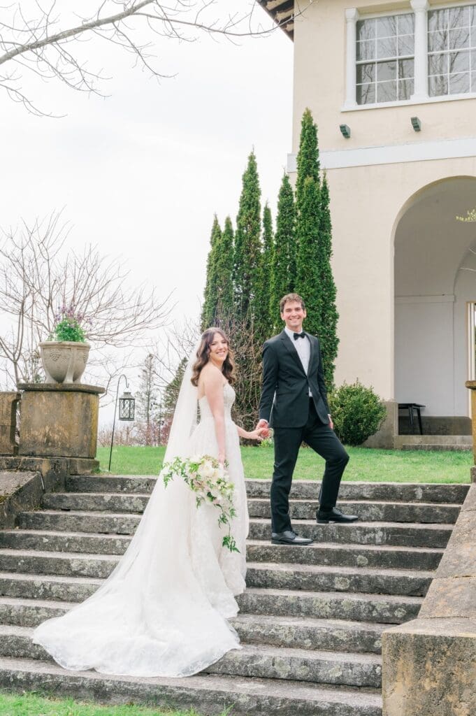 Miranda and Mitch walk up the stairs at Aldworth Manor for a wedding portrait. 