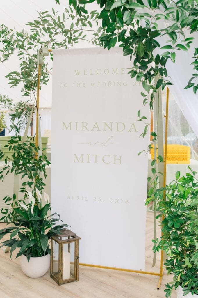 An entryway sign that says "welcome to the wedding of Miranda and Mitch"