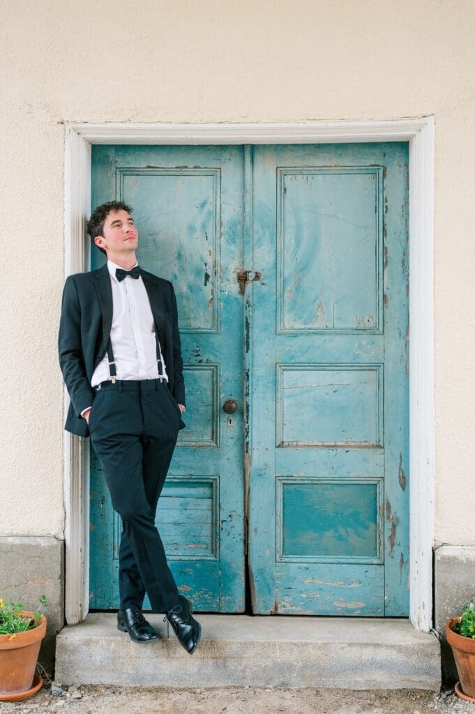 Mitch leans against a doorway and smiles into the distance. 