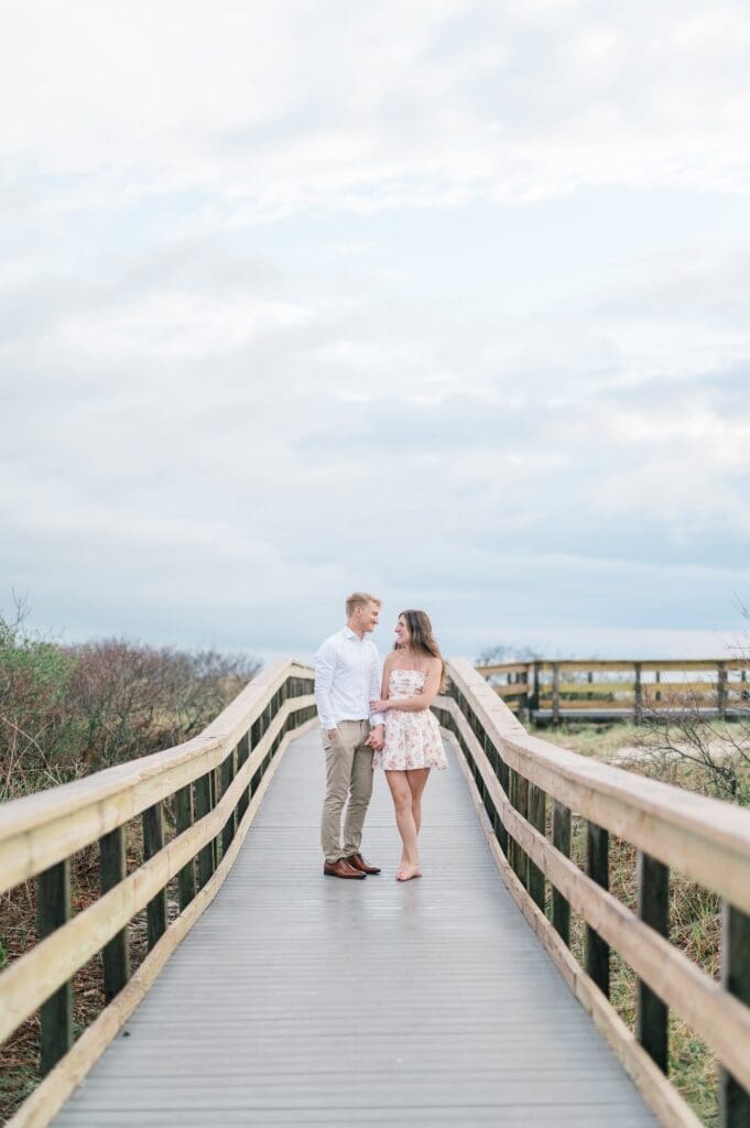 Sydney and Dylan smile and hold hands on the beach. 