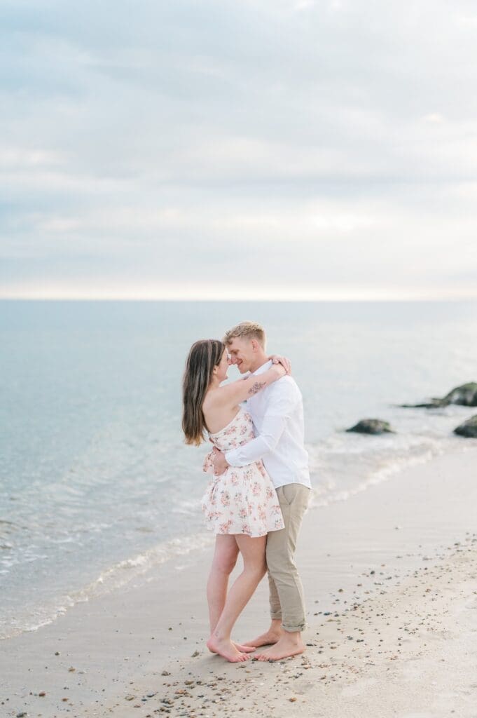 Sydney and Dylan touch noses and smile on the beach. 