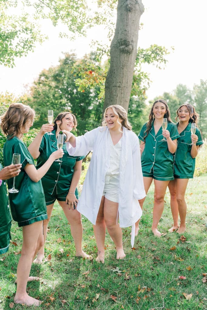 The bride pouring bridesmaids champagne in their matching pijamas. 