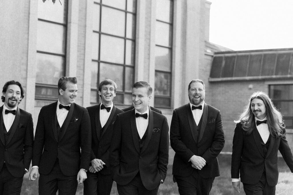 trey and his groomsmen walk and smile at one another. 