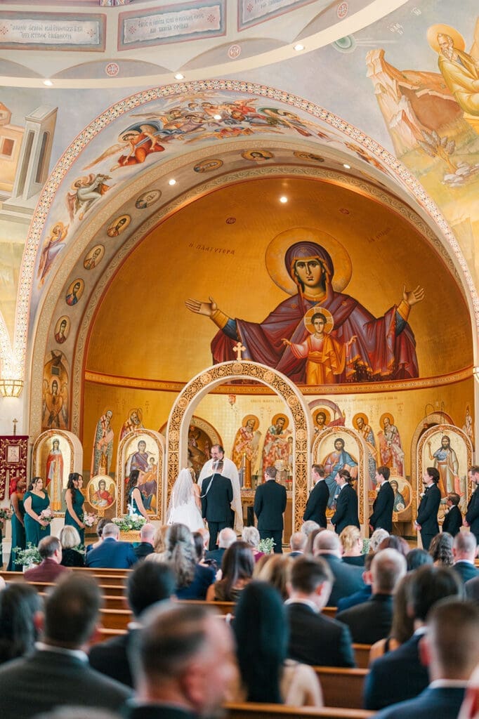 A wide angle photo of the iconography at St. Barbara's while Magdalene and Trey stand on the altar. 
