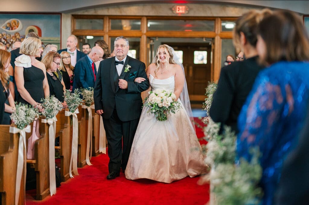 Magdalene smiles as she walks down the aisle with her father. 