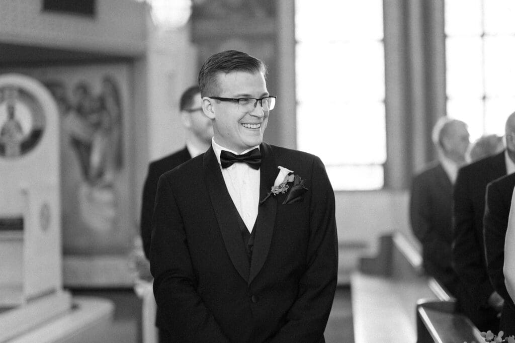 Trey smiles as his bride walks down the aisle at St. Barbara Greek Orthodox Church. 