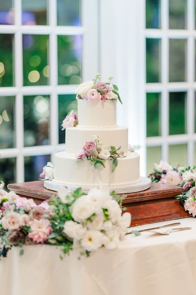 A three-tier classic wedding cake with pink and white florals at Woodwinds. 
