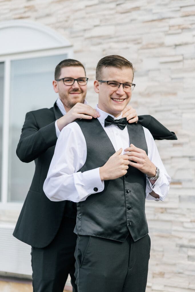 Trey's best man helps him put on his bowtie.  