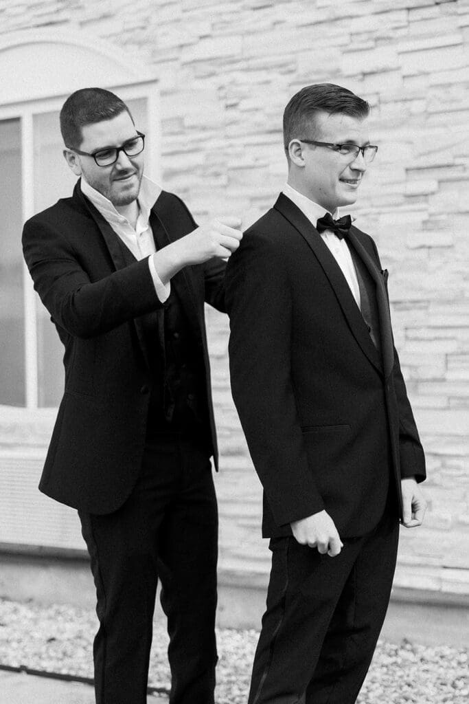 Trey's best man helps him put on his jacket.  