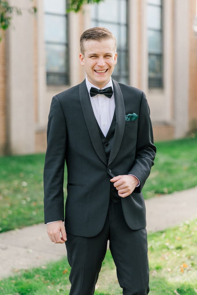 Trey holds his jacket lapel as he smiles. 