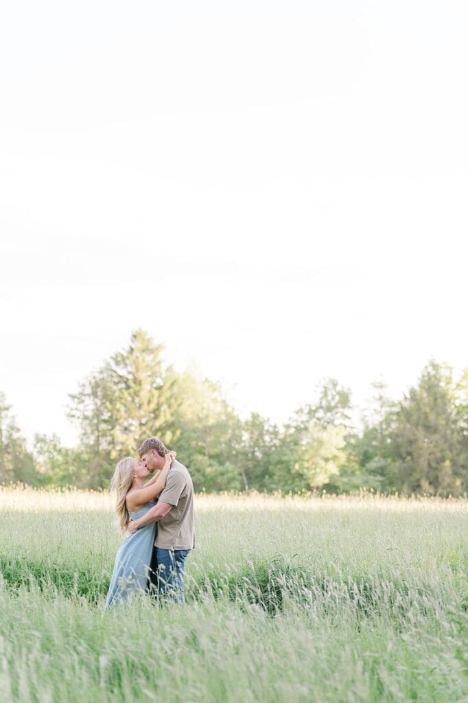 Lois and George kiss in the field at Topsmead State Park. 