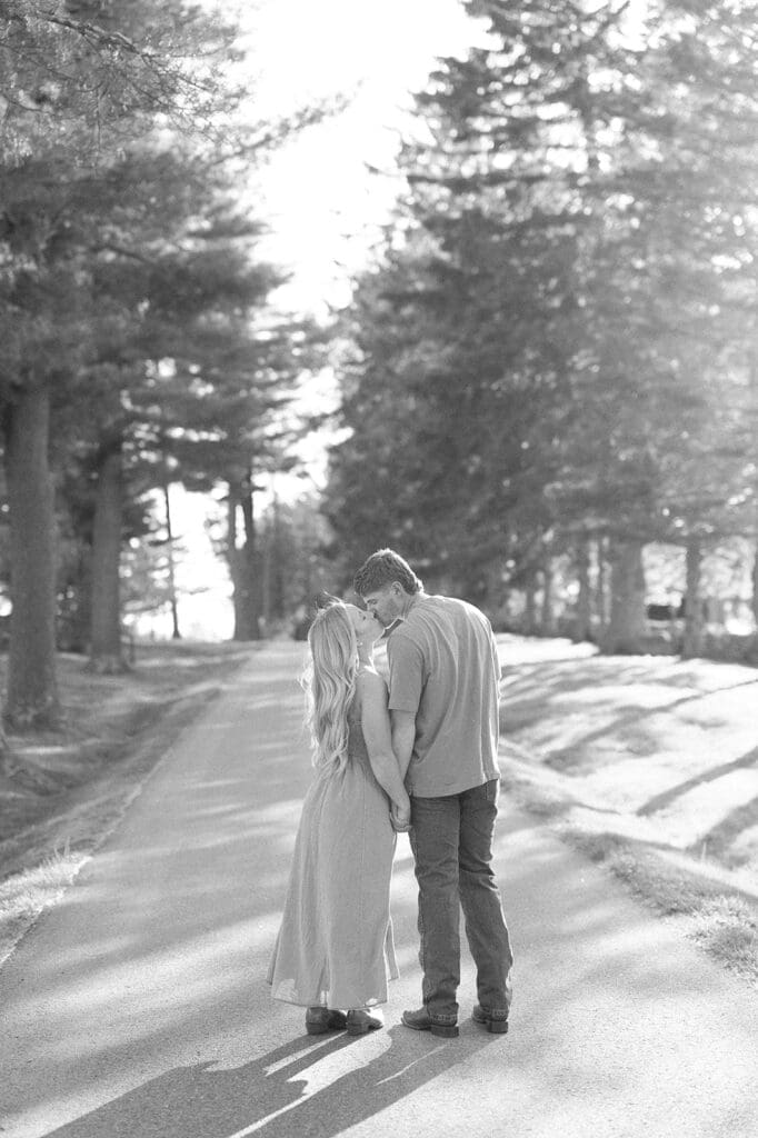 A woman and man kiss at Topsmead State Park for their engagement photos