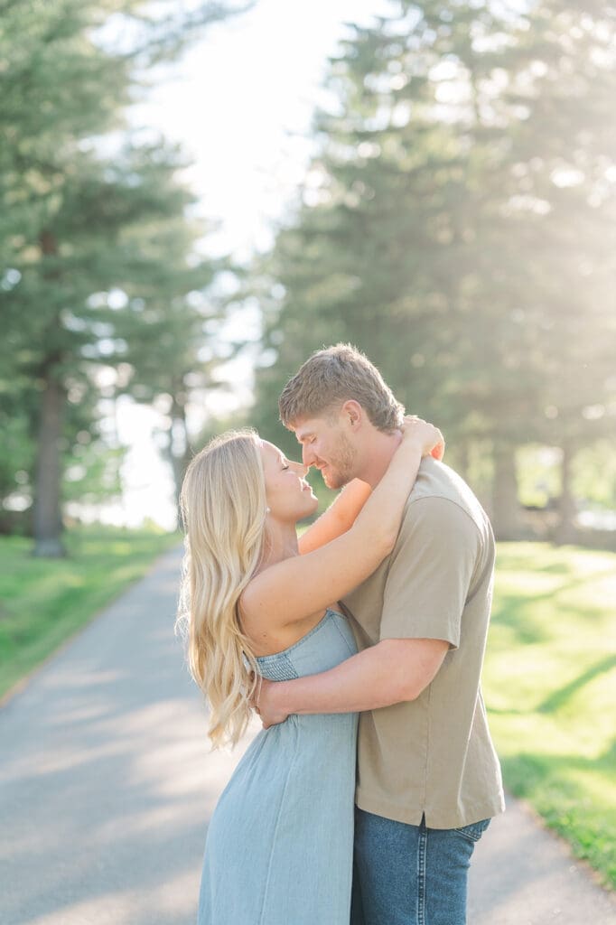 A woman and man nuzzling their noses as the sun peeks out behind them