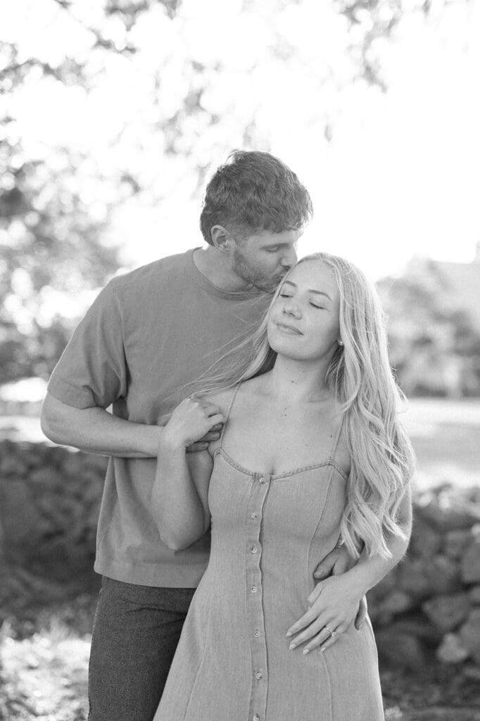 A man kissing his fiancee on her head