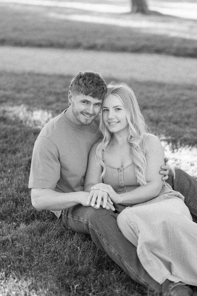 Lois and George sit together on the grass and smile. 