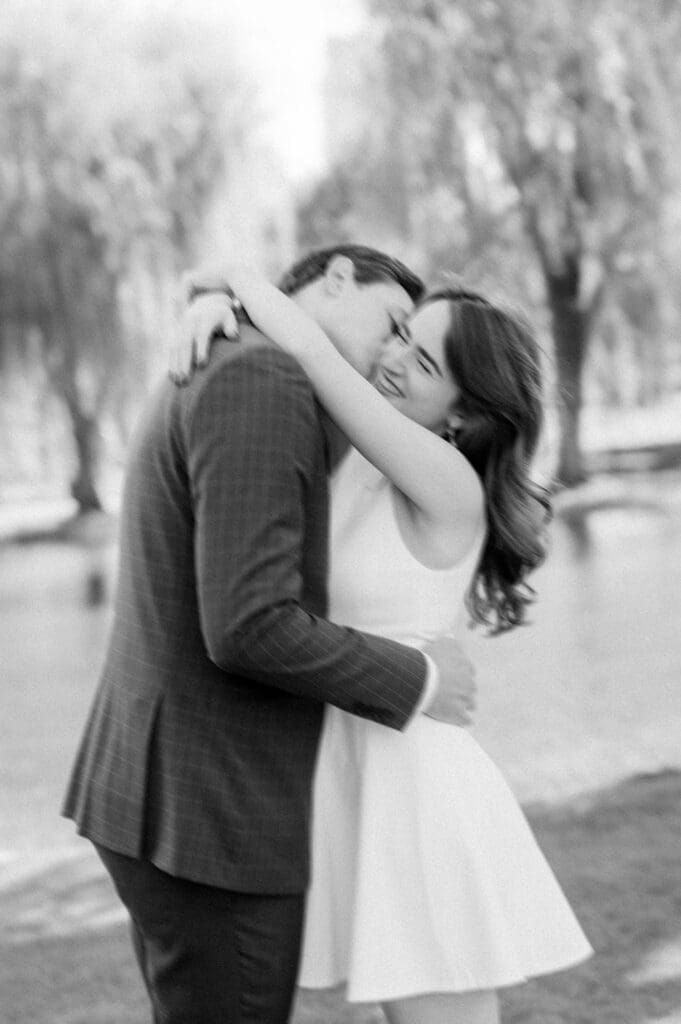 Julia and Brandon swaying and laughing with each other in the Boston Public Garden for engagement photos. 