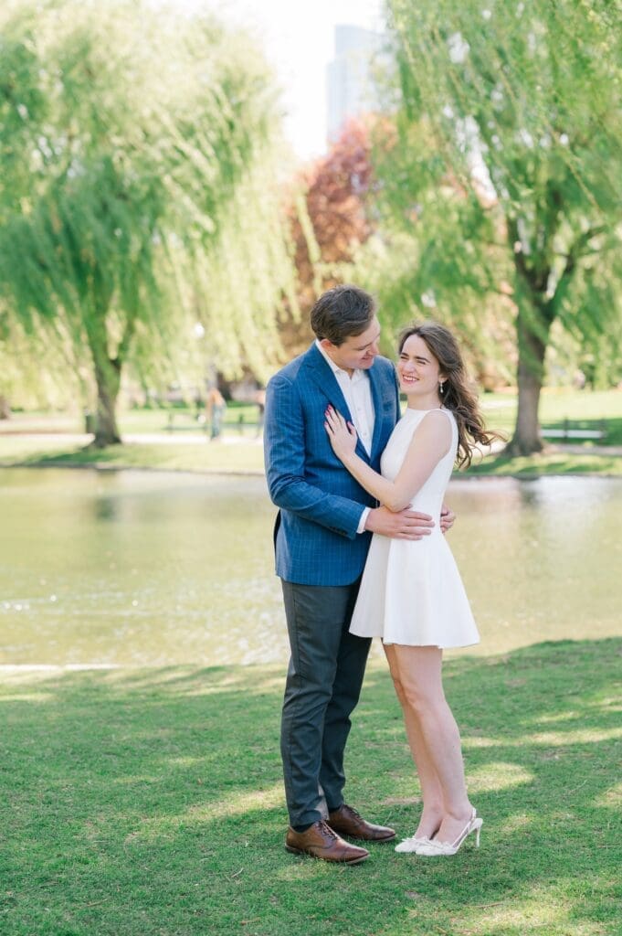 Julia and Brandon laughing together under a willow tree for their spring boston public garden engagement photos