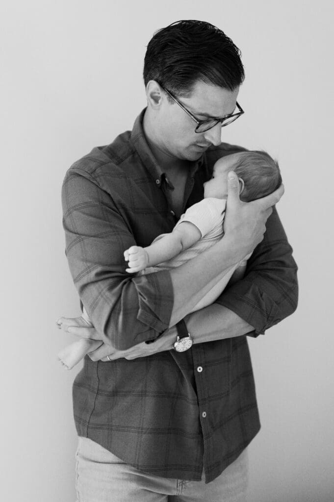 Dad holds the baby in a black and white classic. 