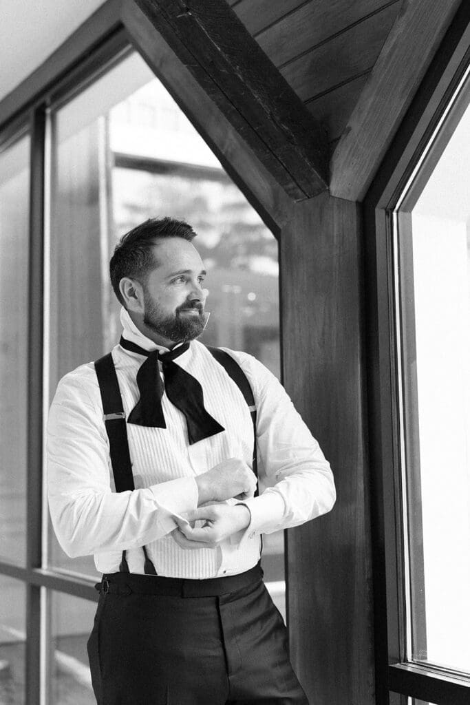 Tom adjusts his cufflinks as he looks out the window at the rainy wedding day. 