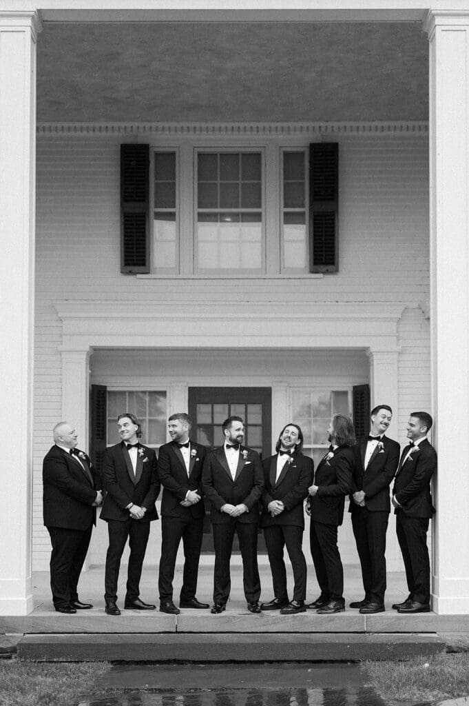 Tom and his groomsmen stand and laugh with one another. 
