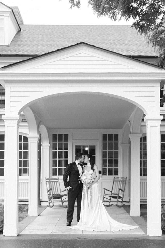 Natalie and Tom kiss under a porch overhang during their rainy wedding day. 