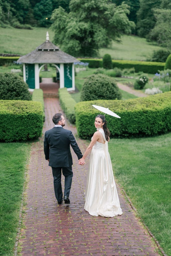 Natalie and Tom hold hands and walk in the sunken garden at Hill-Stead on their rainy wedding day. 