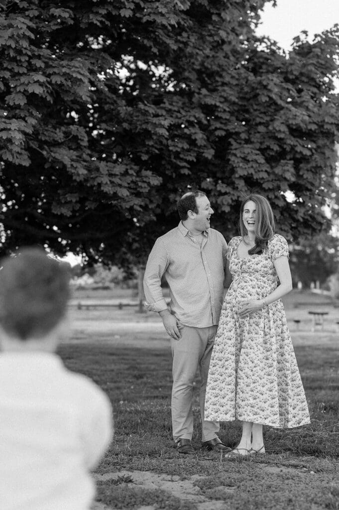 A man and woman laugh as their son runs towards them. 