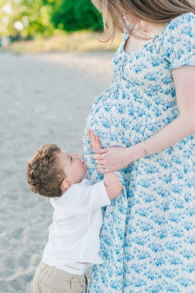 A toddler touches his mom's belly. 