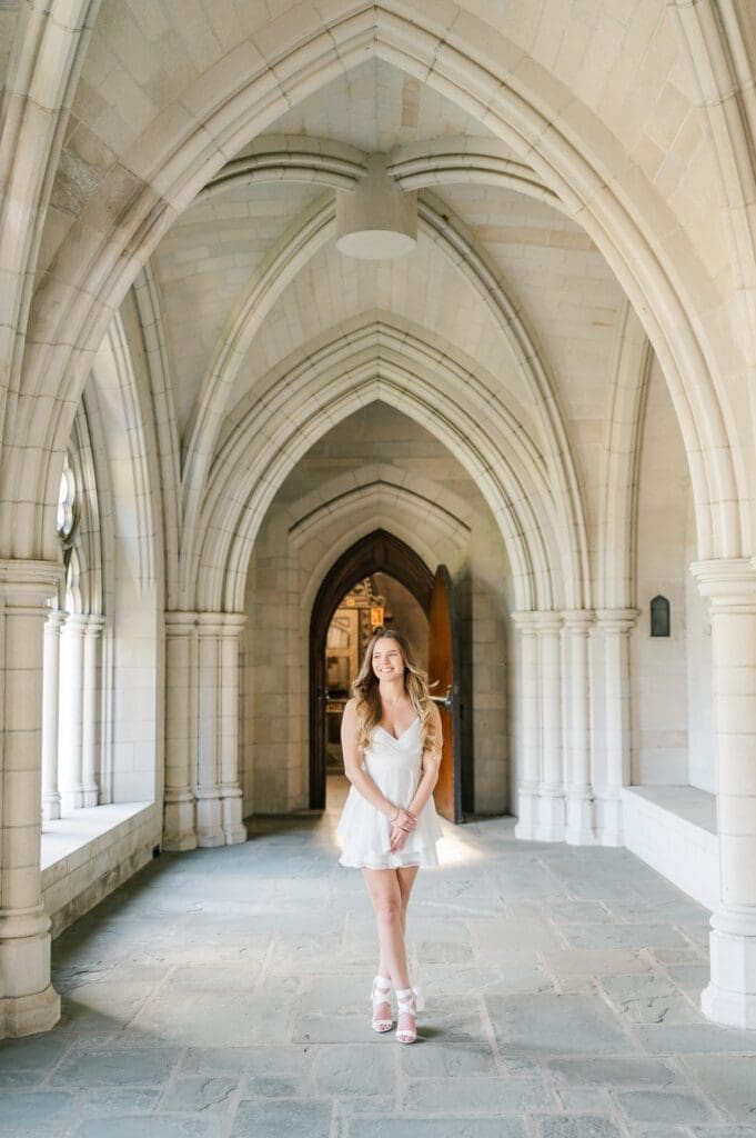 Sophia walks under archways at Trinity college's chapel for her grad photos