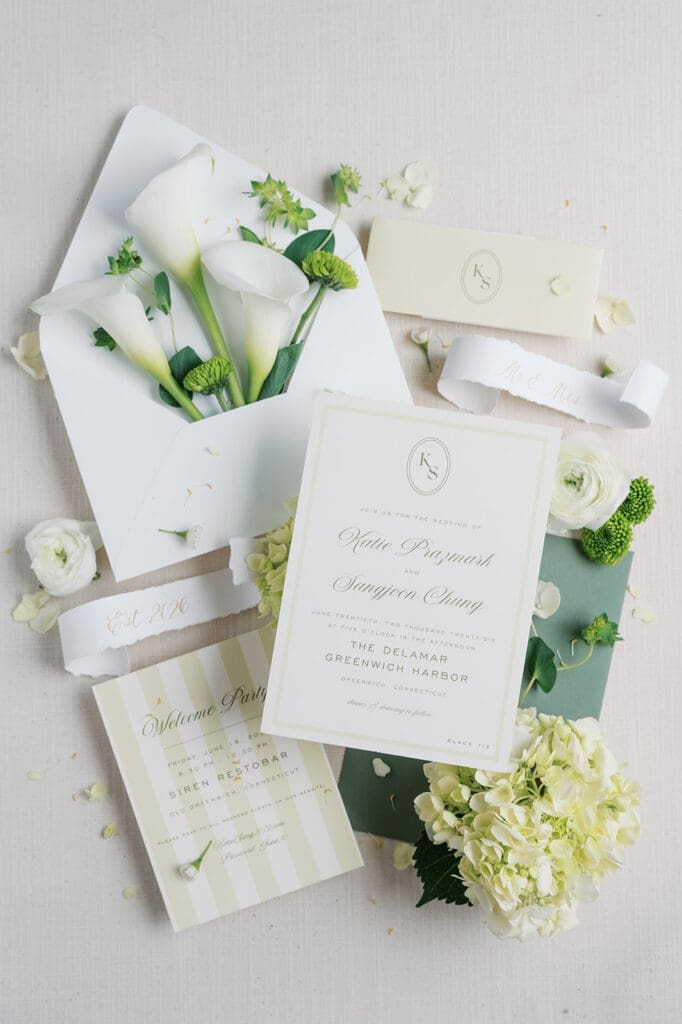 A wedding flat lay with an invitation suite, florals, and scrolls