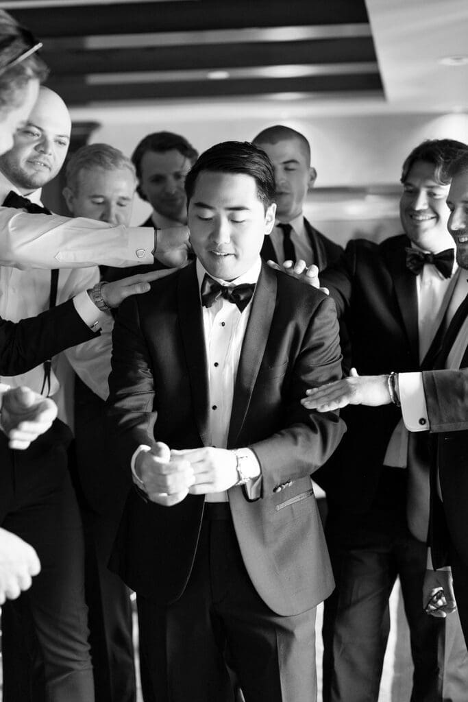 A groom gets ready while his friends crowd around him for his Delamar Greenwich wedding. 