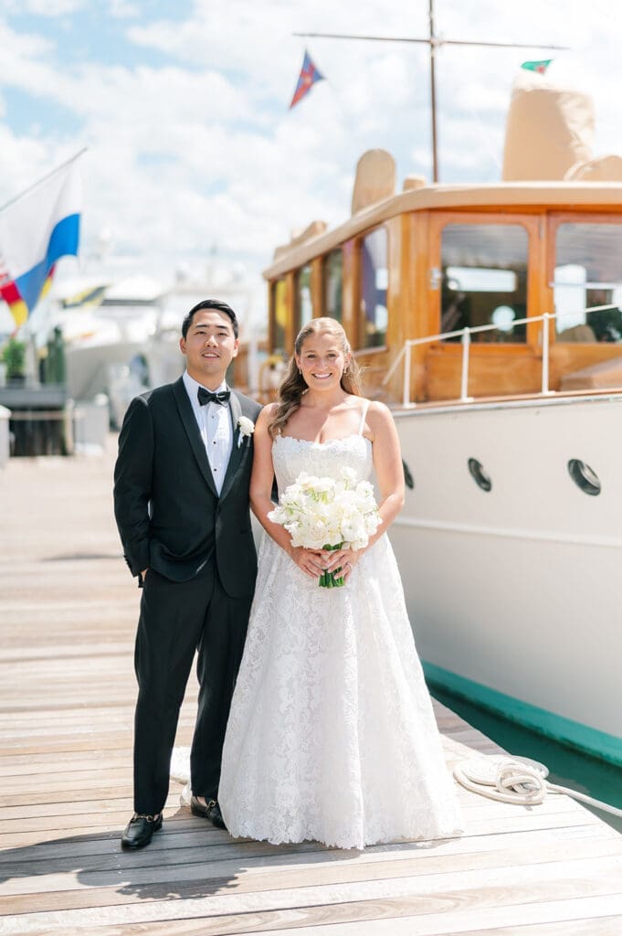 Katie and Sang stand next to boats on the dock in Greenwich. 