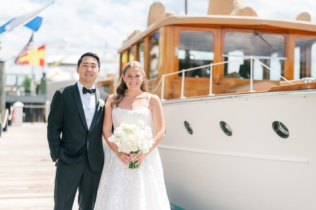 Katie and Sang smile in front of boats on the dock at Delamar Greenwich for their wedding portraits. 