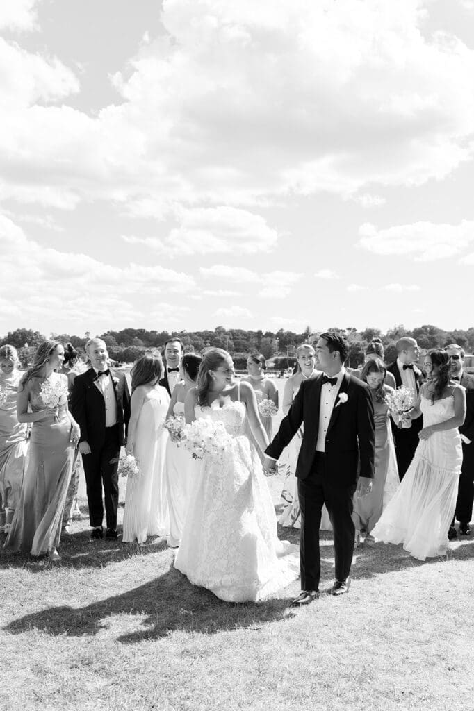 The wedding party walks together and smiles. 