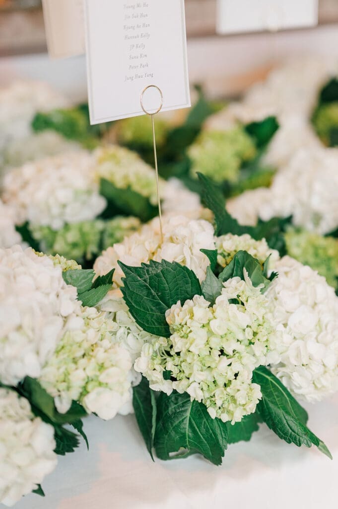 Green and white florals line the tables at their Delamar Greenwich wedding reception. 