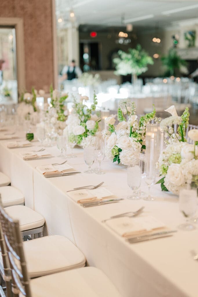 Green and white florals line the tables at their Delamar Greenwich wedding reception. 
