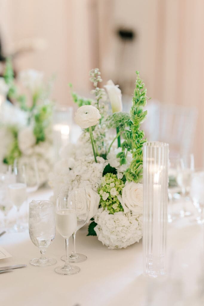 Green and white florals line tables at their wedding reception. 