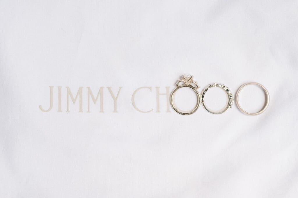 A jimmy choo bag with wedding rings outlining the OO at the end. 