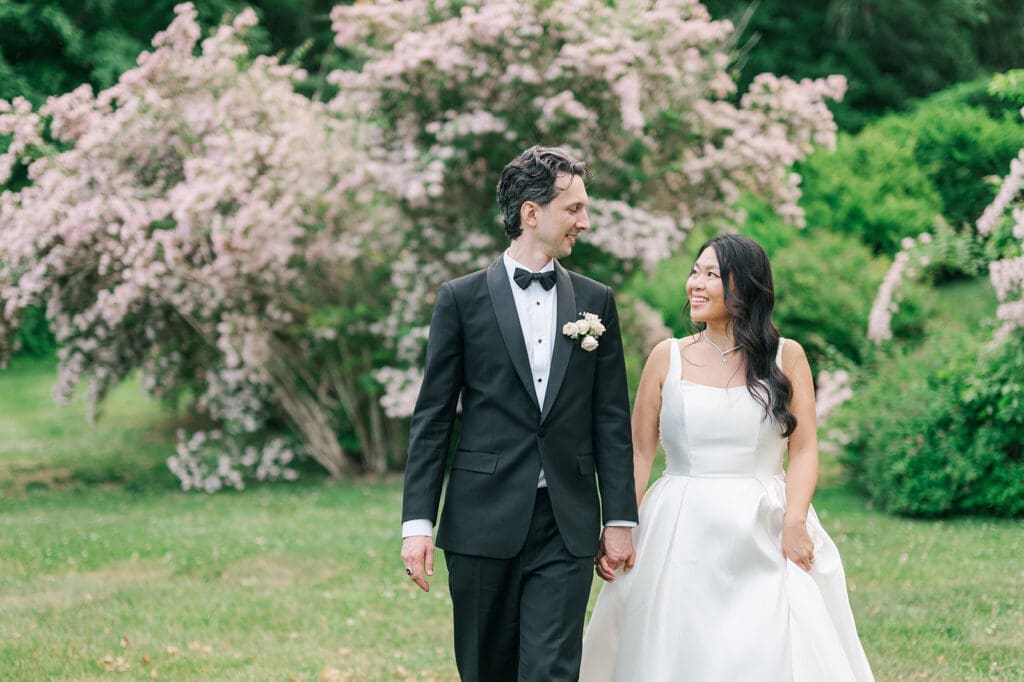 Emily and Chris smile at each other as they walk in the back of the Glen Manor property. 