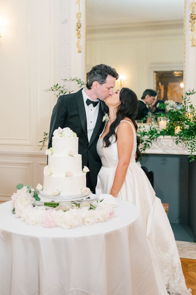 Emily and Chris kiss with their wedding cake