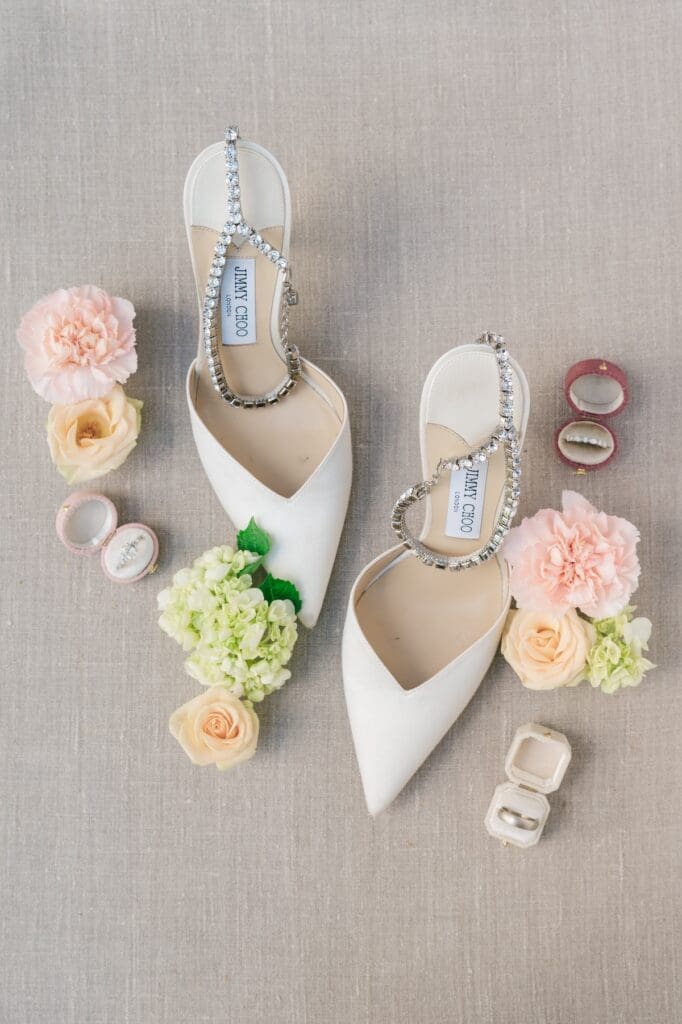 Jimmy Choo shoes flat lay with flowers around them. 