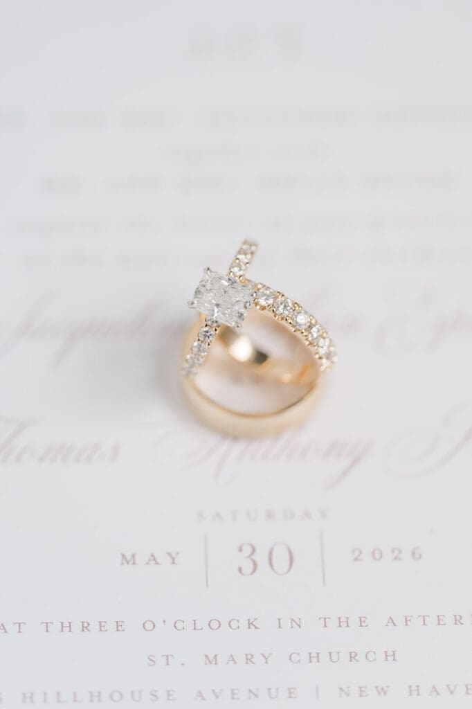 Three wedding rings stacked on top of one another on a wedding invitation suite. 