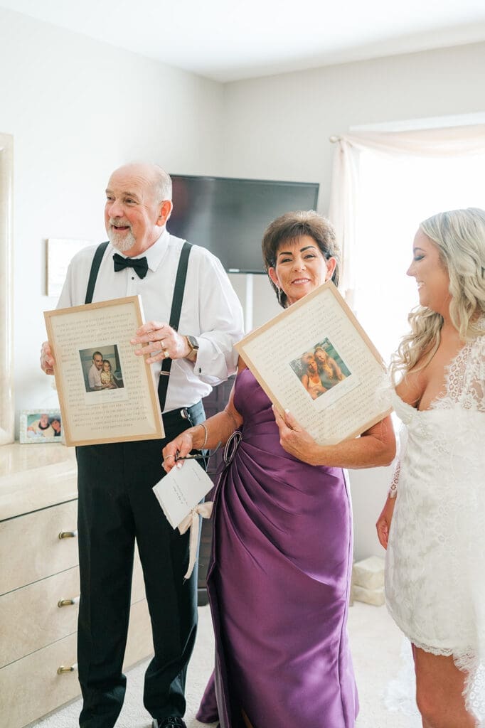 Jacquie standing with her parents as they hold up gifts that she made for them. 