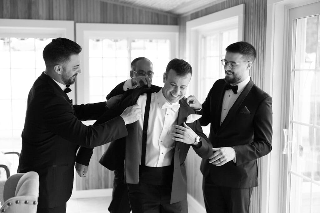 Groomsmen help Thomas put on his suit jacket for his Anthony's Ocean View wedding