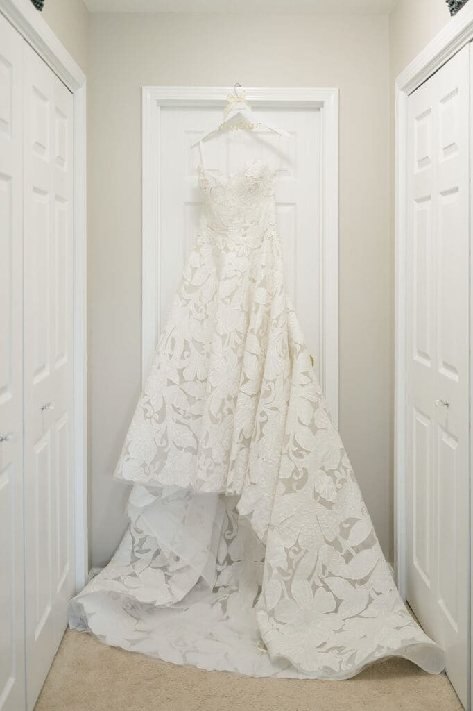 Jacquie's wedding dress hangs from a hanger that says "The Bogens"