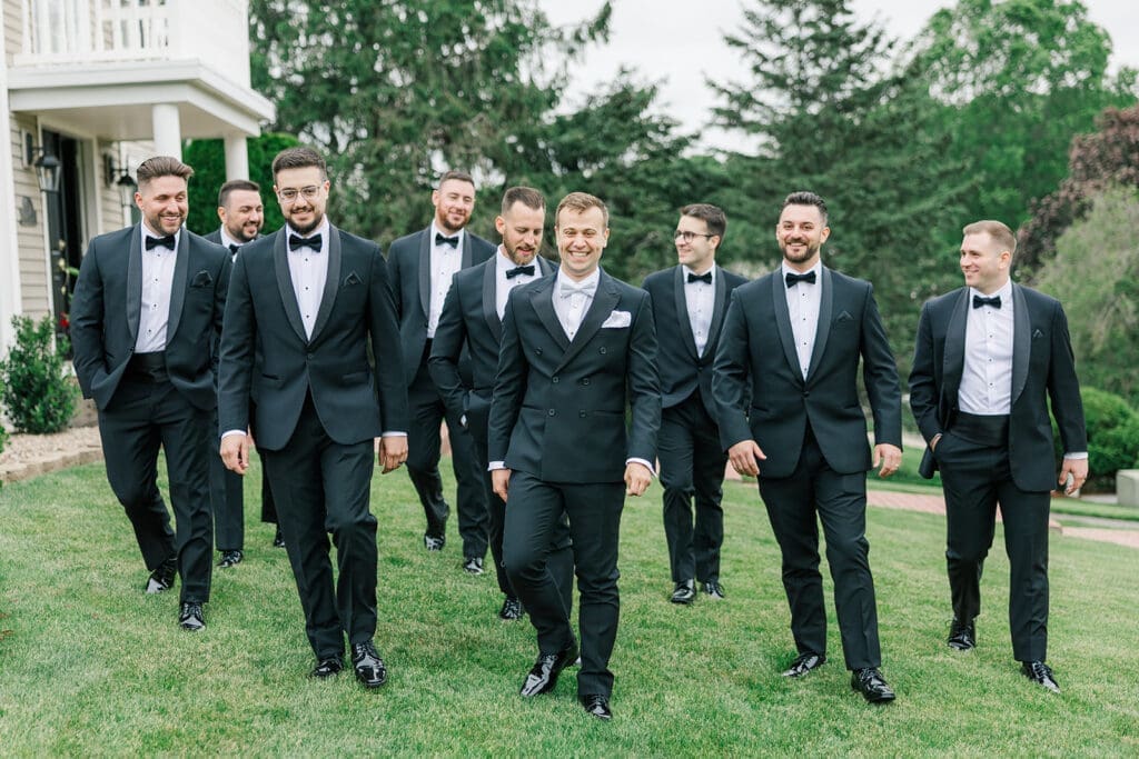 Thomas and his groomsmen walk on the grass outside. 